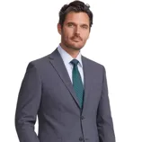 A man is wearing a tailored gray suit with a classic button-up shirt and a green tie, paired with dark dress shoes.