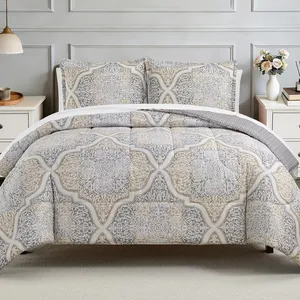 A bed is adorned with a comforter and pillow set featuring an intricate, symmetrical pattern in shades of gray and beige. The room includes a nightstand, lamp, and a vase with flowers.