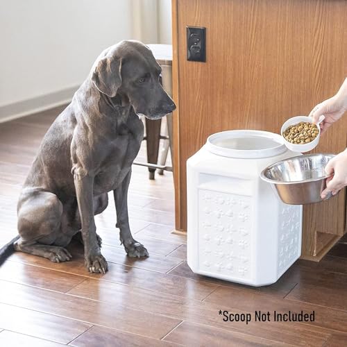 A large dog sits next to a white, textured pet food container, while someone pours kibble from a bowl. Note: Scoop not included.