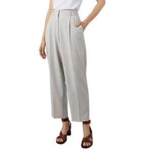 A person is wearing high-waisted, light grey pleated pants paired with a white top and brown strappy sandals.