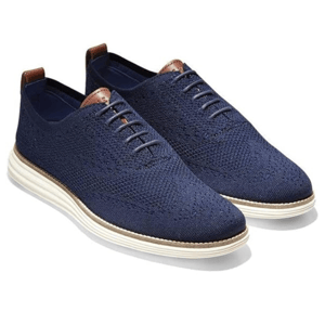 Cole Haan Original Grand Sneakers feature a navy knit upper with a sleek lace-up design, leather accents, and a contrasting white sole for a modern casual look.