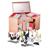 MAC advent calendar featuring a variety of cosmetics, including lipsticks, lip gloss, mascaras, eyeliners, eyeshadows, face creams, and makeup accessories, housed in a stylish rose gold box with numbered compartments.