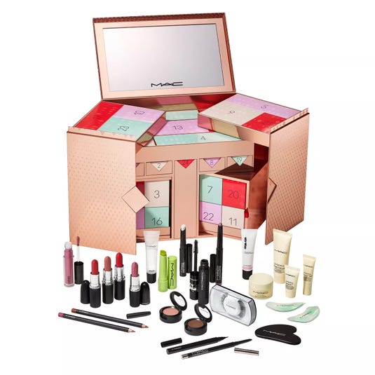 MAC advent calendar featuring a variety of cosmetics, including lipsticks, lip gloss, mascaras, eyeliners, eyeshadows, face creams, and makeup accessories, housed in a stylish rose gold box with numbered compartments.