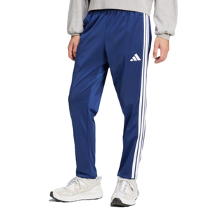 Blue Adidas track pants featuring white three-stripe detailing on the sides, an elastic waistband, and the Adidas logo on the thigh. The pants are paired with white sneakers.