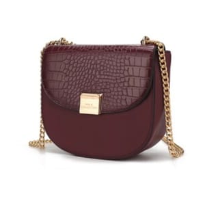 A burgundy handbag with a crocodile-textured flap, gold chain strap, and a square gold plaque.
