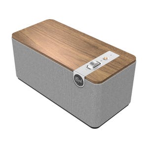 The Klipsch The One Plus Speaker features a sleek design with a wooden top and fabric-covered body, has a manual volume dial, and two control buttons.