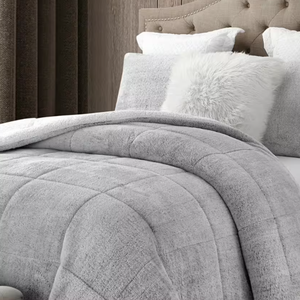 Gray quilted comforter on a bed with white and gray pillows.