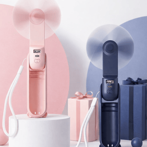 Two portable handheld fans, one pink and one blue, with USB charging ports are displayed on a round pedestal, accompanied by gift boxes in matching colors.