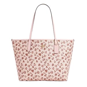 A Coach Outlet tote bag with pink leather and a rose print pattern, featuring long straps and a small hanging tag.