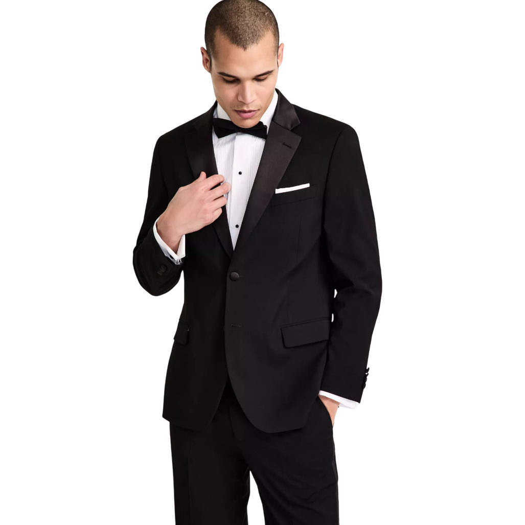 A man is wearing a classic black tuxedo with a satin lapel, a white dress shirt, and a black bow tie.