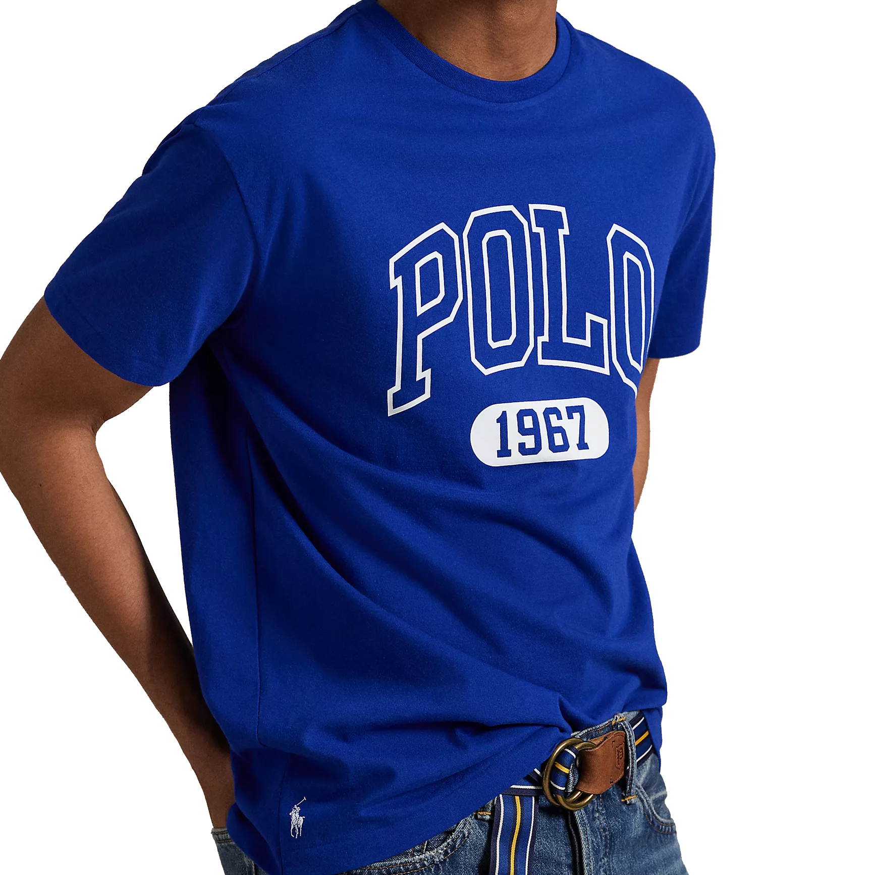 Royal blue t-shirt featuring \“POLO 1967\“ in large white lettering, paired with denim jeans and a striped belt. A small polo player logo is visible near the hem.