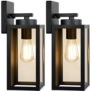 Two rectangular black outdoor wall lights showcasing exposed filament bulbs inside clear glass panels, mounted on a flat backing plate.