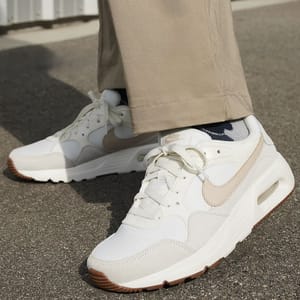 A pair of white Nike Air Max shoes with beige accents and a brown outsole.