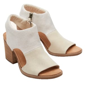 TOMS Eliana Heeled Sandals feature a peep-toe design with a block heel, a neutral fabric upper, and side zippers for easy wear. The contrasting tan accents add a stylish touch, making them ideal for casual or semi-formal outfits.
