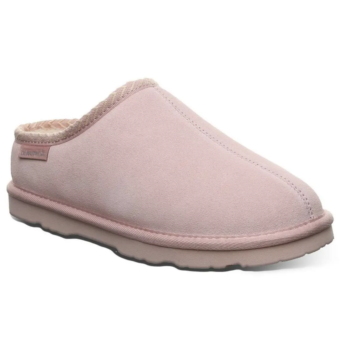 A pink slip-on slipper with a soft, suede-like exterior and a cozy interior lining, featuring a slightly elevated sole and branded tag on the side.