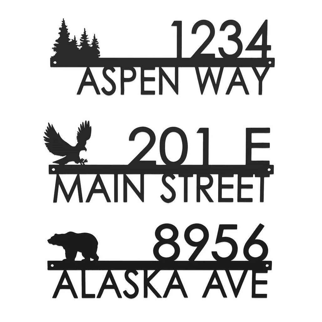 Three metal address plaques with silhouette designs: one features trees and reads \“1234 Aspen Way,\“ another has an eagle with \“201 E Main Street,\“ and the third shows a bear with \“8956 Alaska Ave.\“
