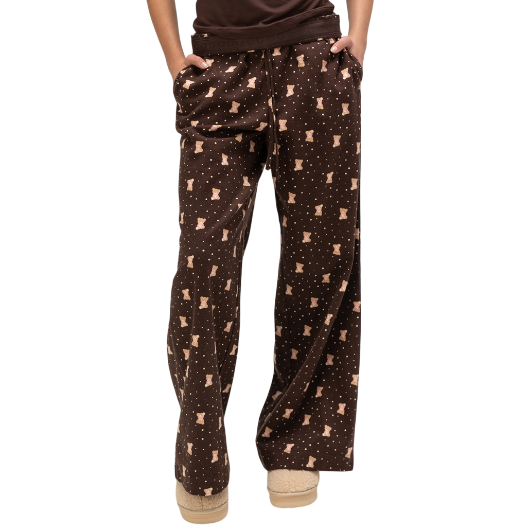 Brown pajama pants with a teddy bear pattern and dots, paired with beige slippers.
