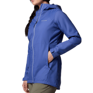 A woman is wearing a blue Columbia hooded jacket with a front zip closure and two zippered pockets, paired with olive pants.