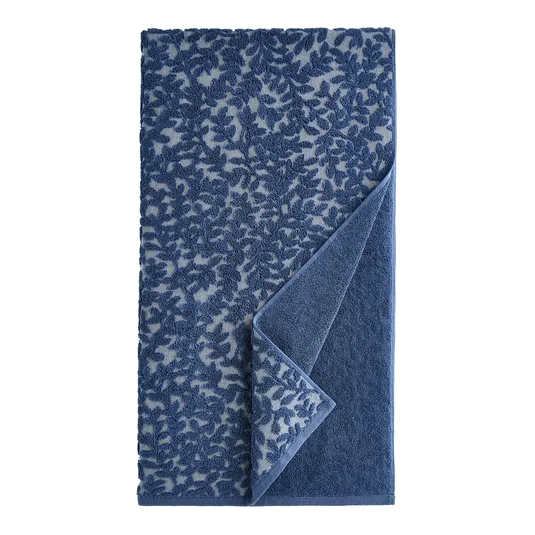 A blue towel featuring a leafy pattern with the fabric slightly folded to show the reverse side, which is a solid blue color.