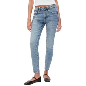 A person wearing light blue skinny jeans paired with a white top and black ballet flats.