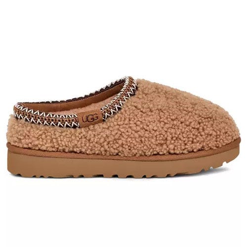 A brown, cozy UGG slipper with a textured, fluffy exterior and a cushioned sole, featuring embroidered trim around the opening.