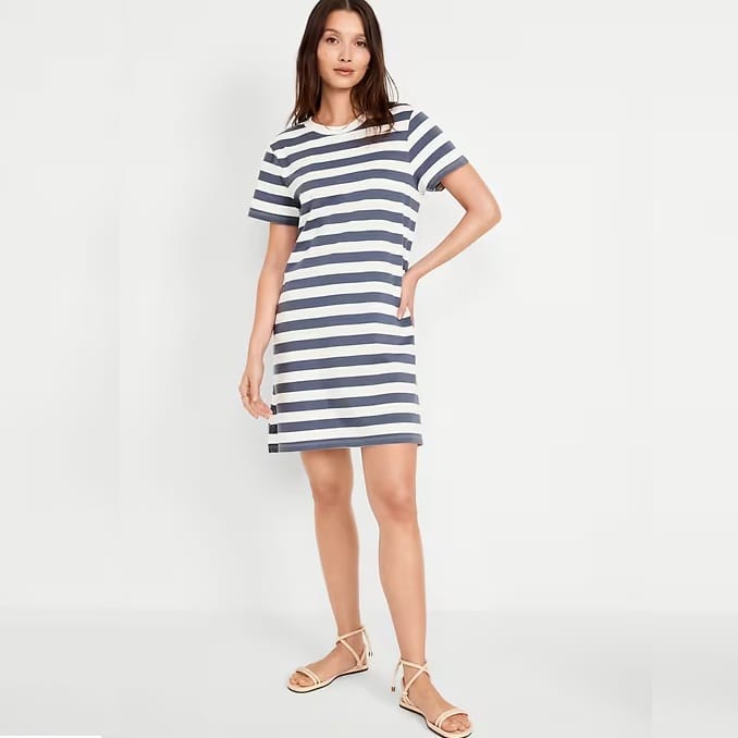 A woman is wearing a horizontal-striped, short-sleeved dress paired with beige strappy sandals.