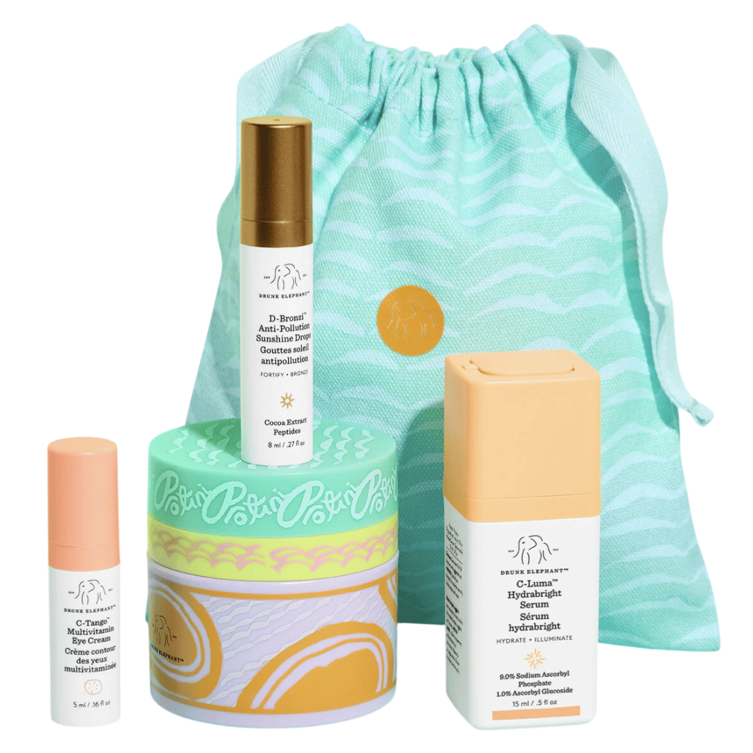 Skincare set featuring Drunk Elephant products: C-Tango Multivitamin Eye Cream, D-Bronzi Anti-Pollution Sunshine Drops, Protini Polypeptide Cream, and C-Firma HydraBright Serum. Presented with a decorative drawstring pouch for storage.