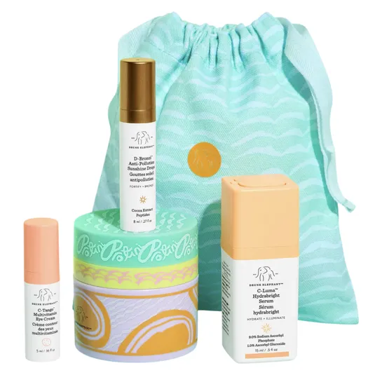 Skincare set featuring Drunk Elephant products: C-Tango Multivitamin Eye Cream, D-Bronzi Anti-Pollution Sunshine Drops, Protini Polypeptide Cream, and C-Firma HydraBright Serum. Presented with a decorative drawstring pouch for storage.