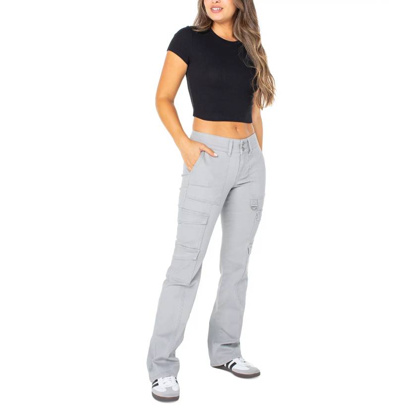 A woman stands wearing a cropped black T-shirt and light grey cargo pants paired with white sneakers.