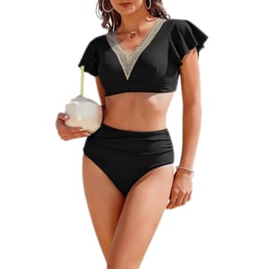 A woman is wearing a black two-piece swimsuit with a v-neck design and short sleeves, holding a coconut.