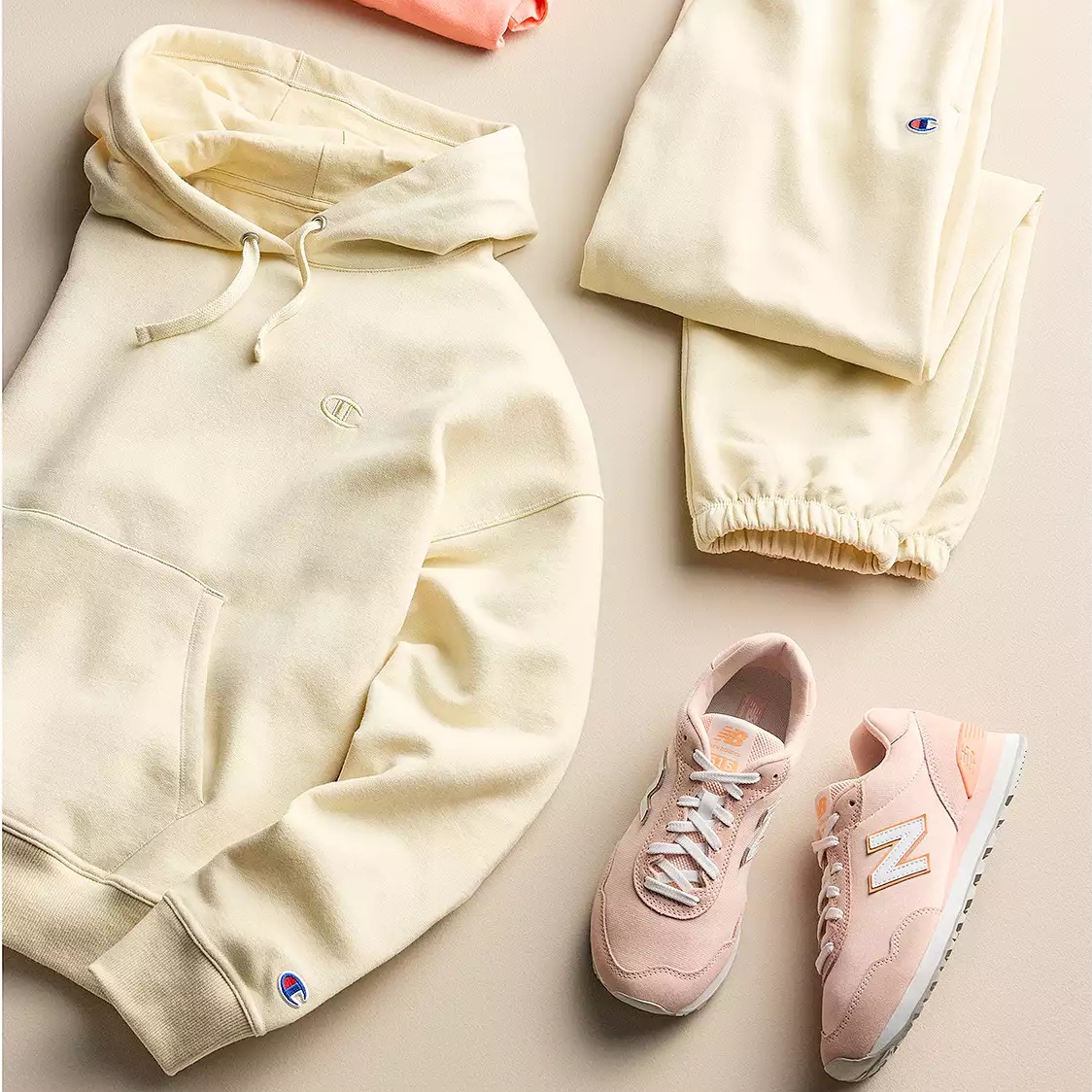 A cream-colored hoodie and sweatpants set paired with pink New Balance sneakers.