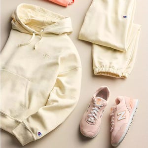 A cream-colored hoodie and sweatpants set paired with pink New Balance sneakers.