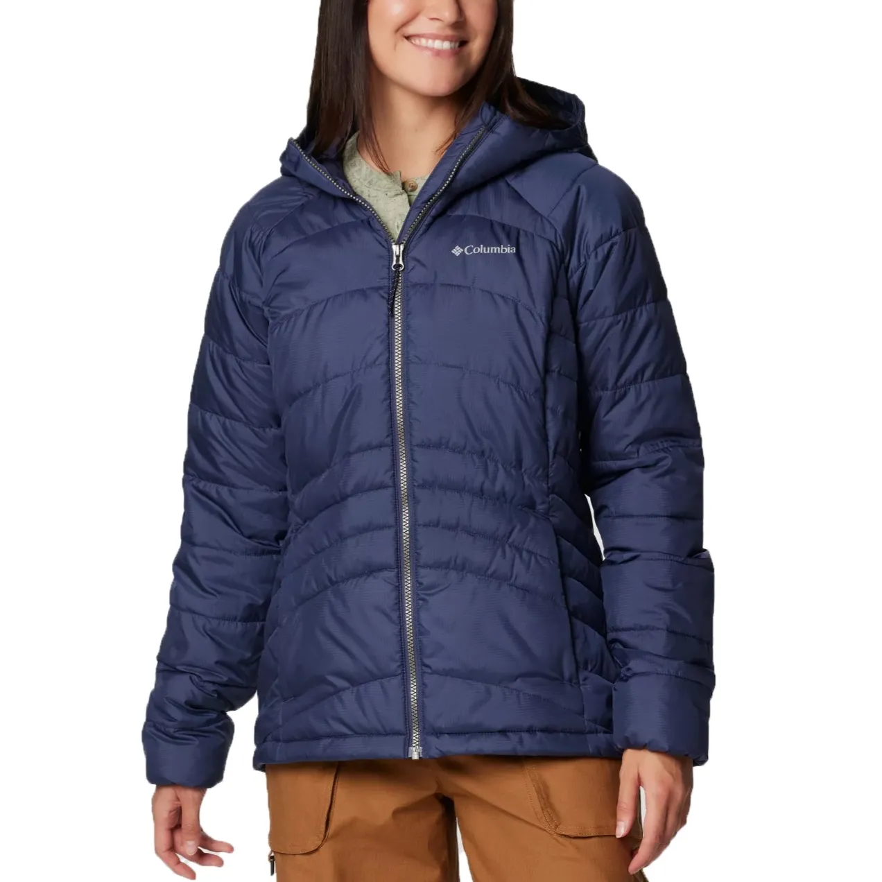 A woman is wearing a hooded Columbia jacket in navy blue with the brand's logo on the left chest, featuring a zip front and side pockets.