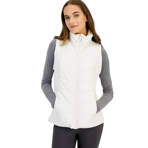 A woman is wearing a white quilted vest over a gray long-sleeve shirt with black pants.