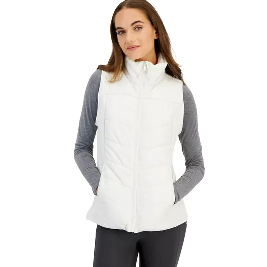 A woman is wearing a white quilted vest over a gray long-sleeve shirt with black pants.