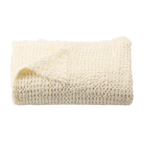 A folded, off-white, textured throw blanket with a waffle weave pattern.