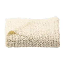 A folded, off-white, textured throw blanket with a waffle weave pattern.