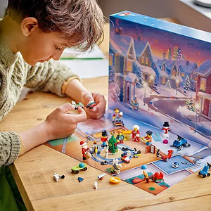 A child is engaged with a LEGO advent calendar set, featuring mini-figures and holiday-themed builds on a table.