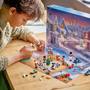 A child is engaged with a LEGO advent calendar set, featuring mini-figures and holiday-themed builds on a table.