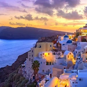 A stunning sunset view over the iconic white buildings with blue domes in Santorini, Greece, overlooking the Aegean Sea.