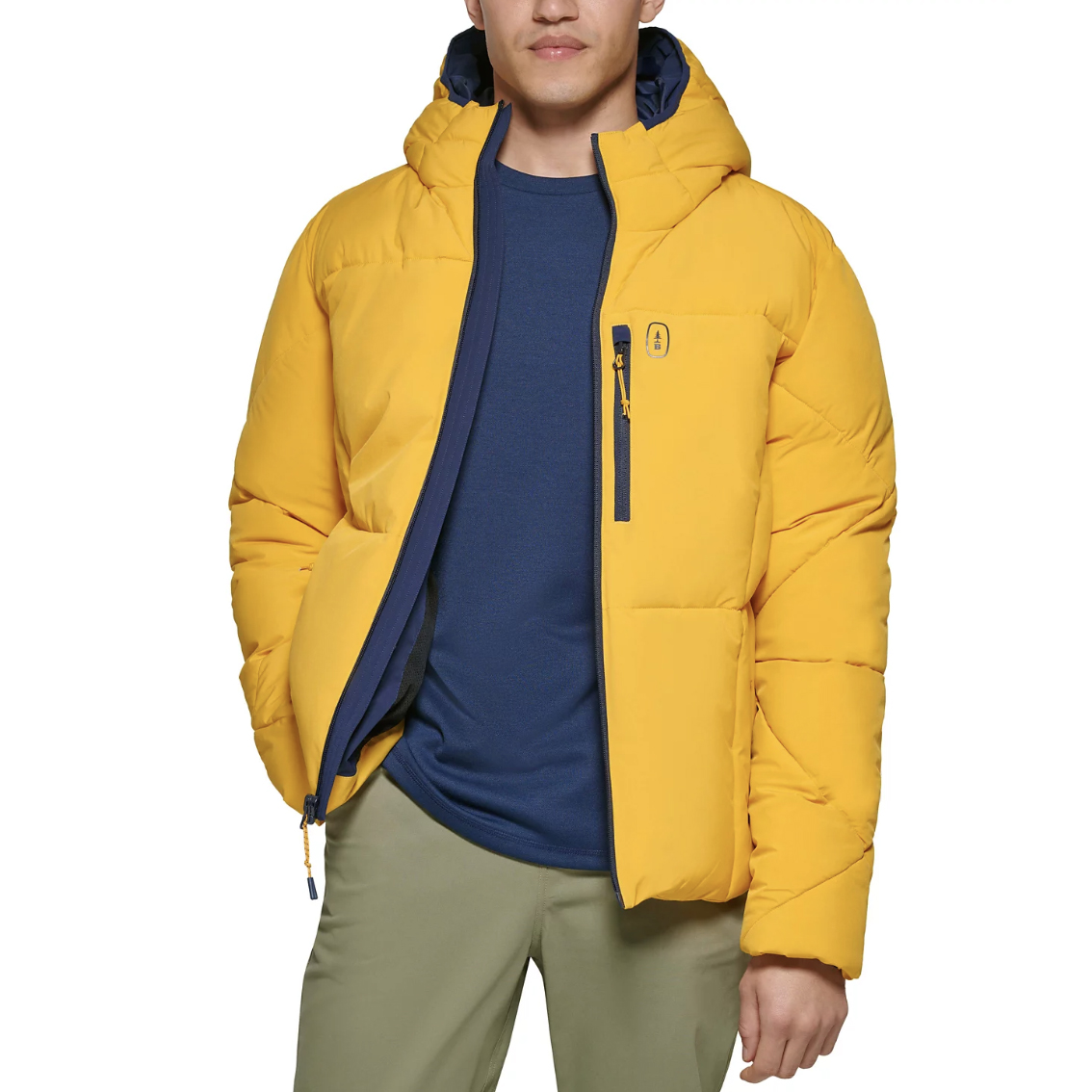 A person is wearing a bright yellow puffer jacket with a hood and a chest zipper pocket, paired with a dark blue shirt underneath and olive-green pants.