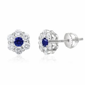 Silver stud earrings with a flower design feature a blue center stone, resembling a sapphire, surrounded by smaller clear stones, resembling diamonds.