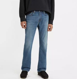 A person wearing light blue denim jeans and a black sweatshirt with black shoes.