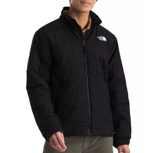 The North Face Men's Junction Jacket is a black, zip-up insulated jacket featuring the brand's logo on the chest. It has a quilted design with a high collar for added warmth.