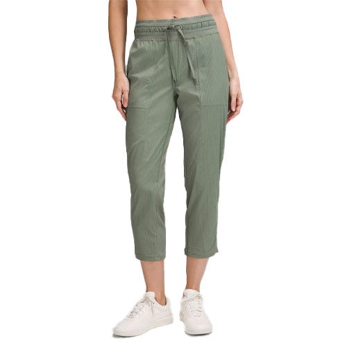 A person is wearing sage green cropped pants with an elastic waistband and drawstring, paired with white sneakers.