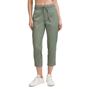 A person is wearing sage green cropped pants with an elastic waistband and drawstring, paired with white sneakers.