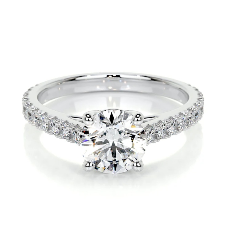 A silver engagement ring featuring a round-cut diamond in a prong setting with a band adorned with smaller diamonds.
