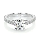 A silver engagement ring featuring a round-cut diamond in a prong setting with a band adorned with smaller diamonds.