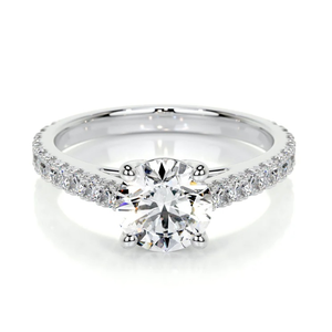 A silver engagement ring featuring a round-cut diamond in a prong setting with a band adorned with smaller diamonds.