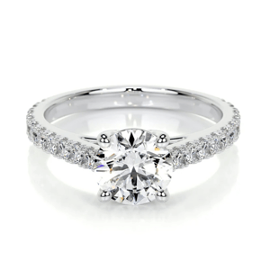 A silver engagement ring featuring a round-cut diamond in a prong setting with a band adorned with smaller diamonds.